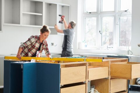 Woman checking level and man drilling in cabinets of kitchen remodel project from We Do Kitchens 2